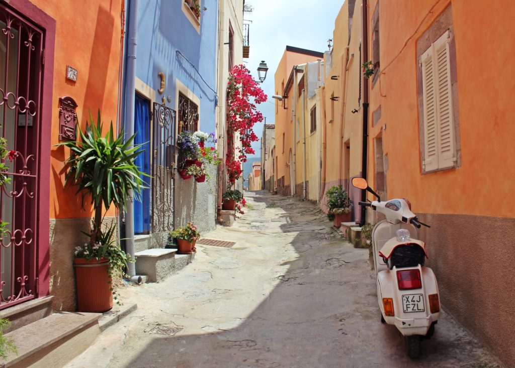 Things to Do in Modena Italy featured by top US travel hacker, Points with Q: image of Italy Alleyway Scooter Colorful Buildings