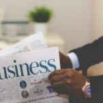 person wearing suit reading business newspaper