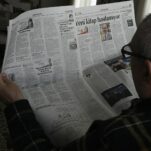 a man reading a newspaper while wearing glasses