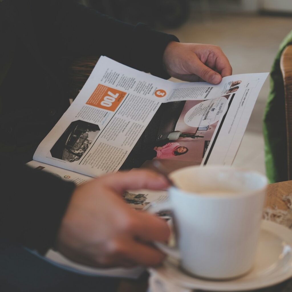 person reading while holding white ceramic mug